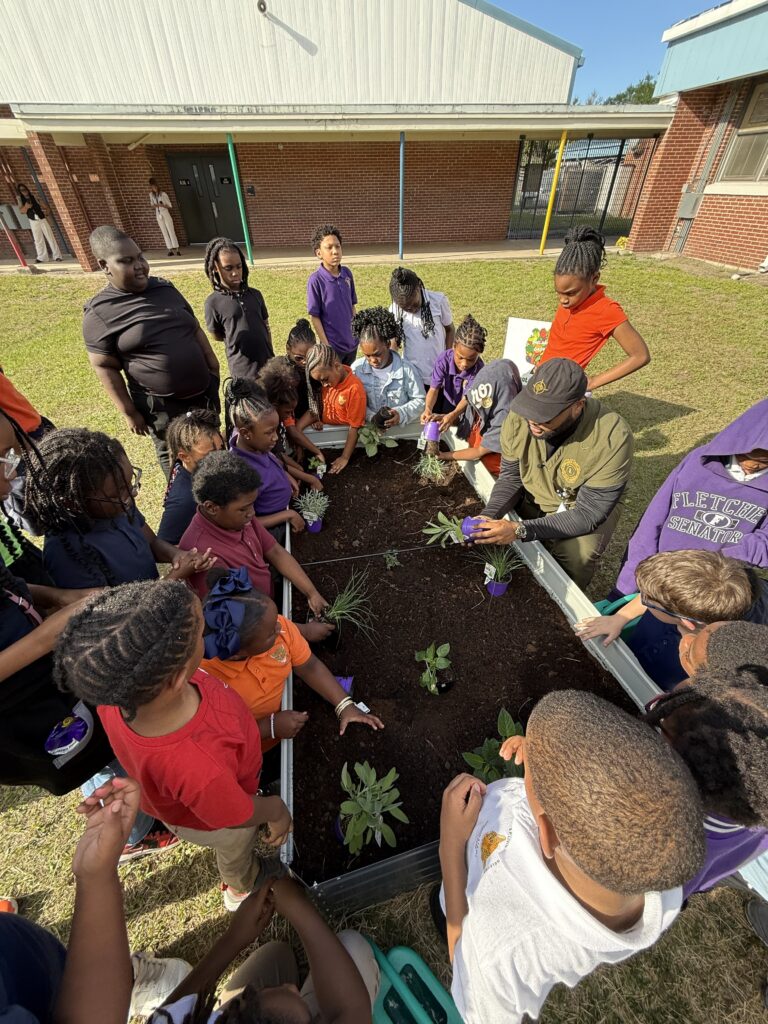 Students at SP Livingston Elementary gather around a raised garden bed. 